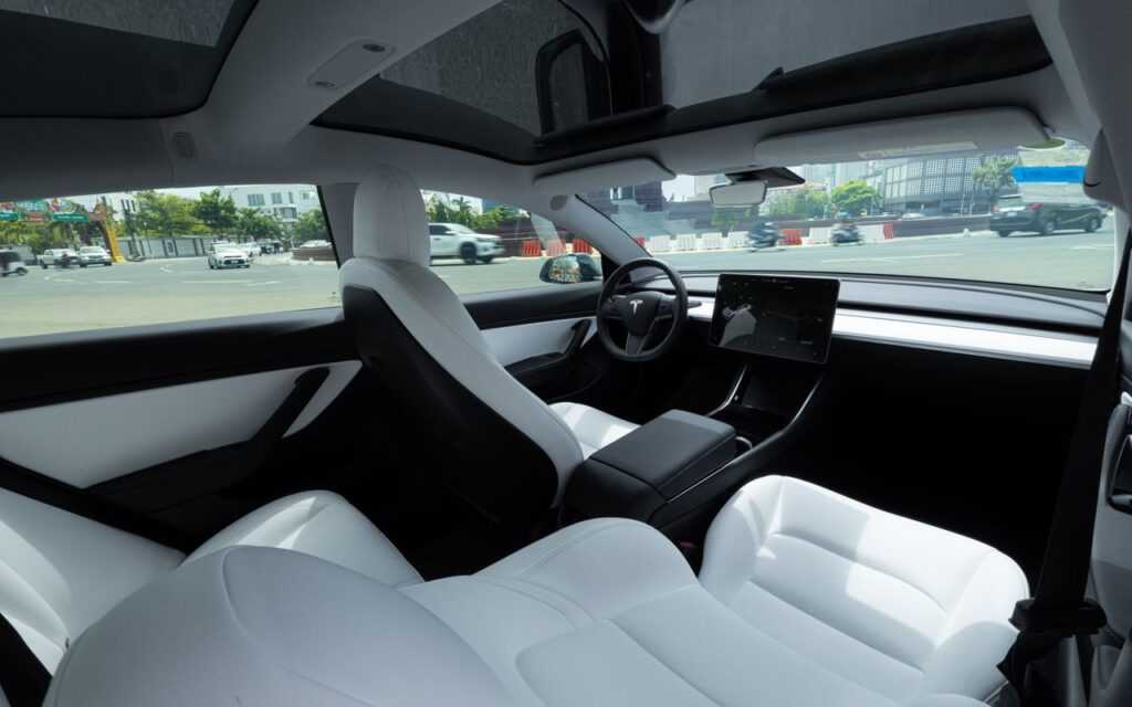 Elegant interior of an electric car featuring luxurious white leather seats and a panoramic view.