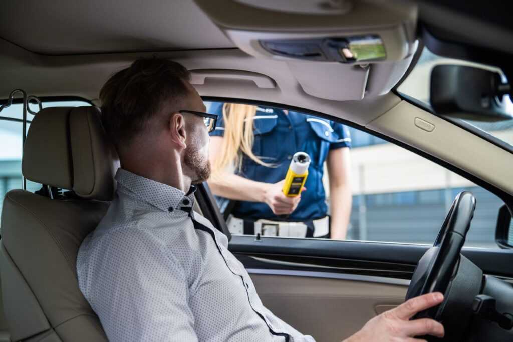Officer administering a breathalyzer test to a driver during a roadside check for safety.